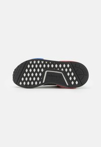 Black shoe sole featuring a honeycomb pattern, with colored accents in blue and red. Textured grip design with an embossed logo.