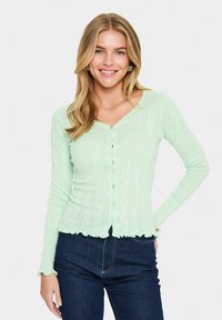 Cardigan long à manches longues vert menthe avec un ourlet festonné, une fermeture à boutons et un motif texturé décoratif sur l'ensemble.