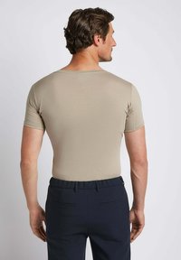 Beige short-sleeve shirt with a rounded neckline, fitted design, and smooth texture, paired with navy pants featuring two back pockets.