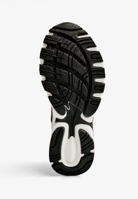 Sko sål med en struktureret sort gummioverflade, der har en hvid detalje og indviklede mønstre for bedre greb.