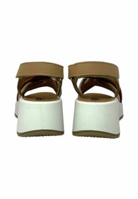 Sandali in pelle marrone con una suola platform bianca spessa, dotati di cinturini incrociati e supporto posteriore per stabilità. Texture liscia e design moderno.