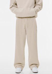 Beige Sweatpants mit elastischem Bund und Kordelzug. Aus weichem Stoff gefertigt, mit weiten Beinen und ohne sichtbare Muster oder Akzente.