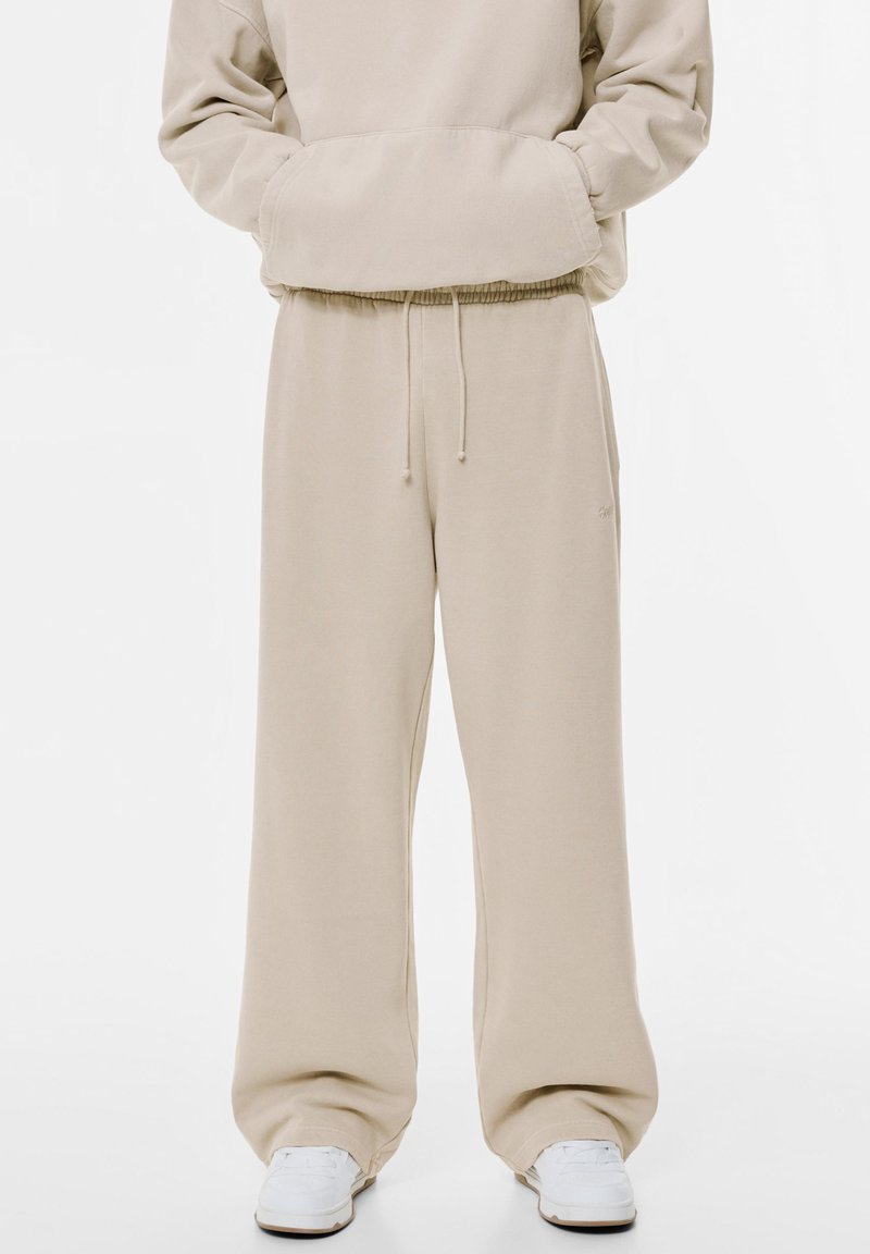 Beige Sweatpants mit elastischem Bund und Kordelzug. Aus weichem Stoff gefertigt, mit weiten Beinen und ohne sichtbare Muster oder Akzente.
