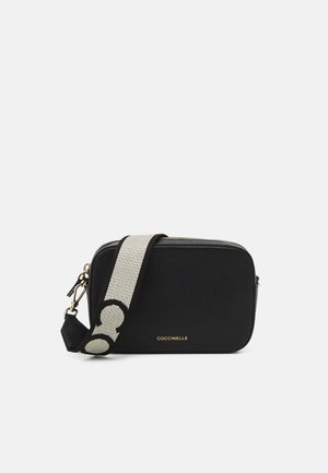 Schwarze rechteckige Leder-Umhängetasche mit breitem beige-schwarzem Gurt mit kreisförmigem Muster und goldenem Markenlogo vorne.