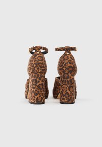 Leopardmønstrede højhælede sko med tyk hæl og ankelrem. Lavet af struktureret stof, med et robust design og gyldne hardware-detaljer.