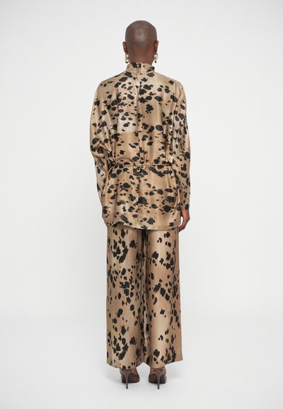 Satin ensemble featuring a beige base with black leopard spots; includes a loose, long-sleeved shirt and wide-leg pants.