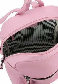 Mochila sintética rosa con una cremallera abierta, que revela un forro interior a rayas en blanco y negro. Presenta una textura suave y herrajes de plata.