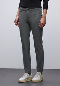 Graue, schmal zulaufende Hosen mit einer glatten Textur. Verfügt über zwei vordere Taschen und ein flaches Vorderteil, kombiniert mit weißen Sneakers.