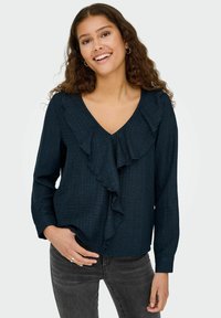 Marineblouse met lange mouwen, een v-hals en een gerimpeld frontdetail. Gemaakt van textiel met een subtiele strepen.