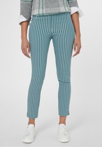 Teal gekleurde broek met een visgraatpatroon, taps toelopende pasvorm en een cropped lengte, gecombineerd met witte sneakers. Gladde stof textuur.