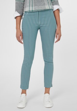 Tealfarbene Hose mit Fischgrätmuster, tapered Fit und verkürzter Länge, kombiniert mit weißen Sneakers. Glatte Stofftextur.