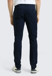 Παντελόνια φόρμας σε ναυτικό μπλε από απαλό ύφασμα, με ίσια γραμμή στα πόδια, δύο πίσω τσέπες και συνδυασμένα με λευκά και μαύρα αθλητικά παπούτσια.