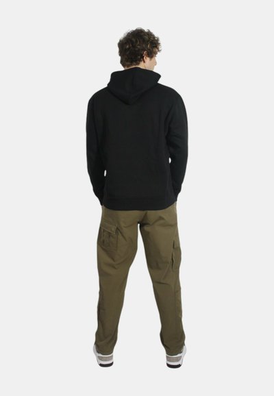 Felpa nera con cappuccio regolabile, abbinata a pantaloni cargo verde oliva con multiple tasche laterali e una vestibilità rilassata.