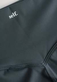 Must lääne tekstuuriga must sportlik kangas, millel on peen sära ja valge "self." logo. Includes õmblustega liitekohad vastupidavuse tagamiseks.