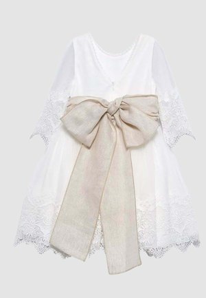 Abito bianco in pizzo a maniche lunghe con bordi smerlati e un grande fiocco beige annodato in vita.