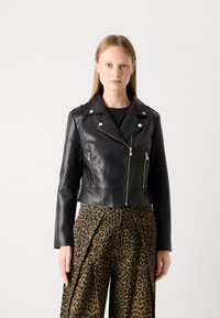 Veste de moto cropped en cuir noir avec des zips argentés et des boutons-pression, dotée d'épaulettes et d'un design élégant et ajusté.