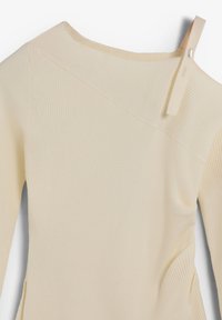 Top beige de canalé con diseño de hombros descubiertos, que presenta una tira estrecha y detalle de costura diagonal, textura suave y forma ajustada.