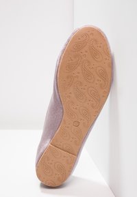 Sula av en lavendelfärgad sammetssko med ett paisley- och hjärtformat mönster på en tan gummisula, storlek 39 markerad nära fotvalvet.