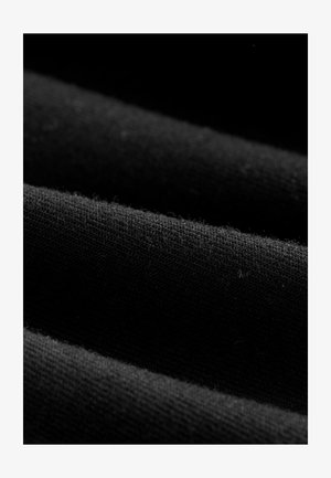 Tessuto nero che mostra una texture a coste con una leggera peluria. L'immagine rivela strati con bordi lisci e un colore uniforme in tutto.