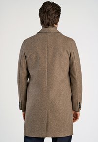 Manteau en laine marron au fit ajusté, doté d'un col cranté, d'une fente unique et de poignets boutonnés. Texture lisse et design minimaliste.