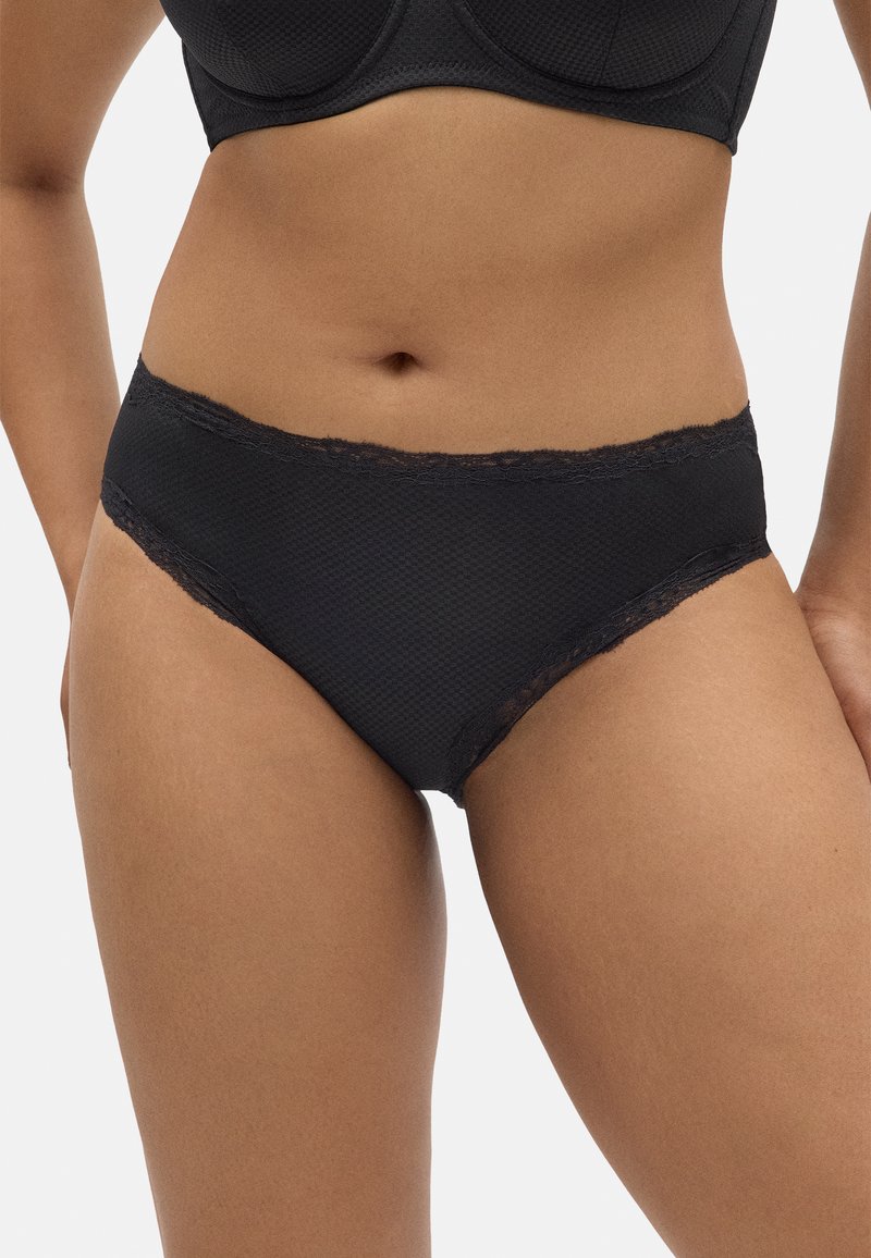 Bañador negro en forma de braguitas con un material texturizado, encaje en el cinturón y un corte de altura media para un ajuste cómodo.