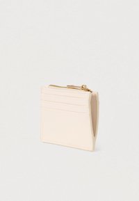 Portefeuille rose clair en cuir lisse, comprenant une poche zippée, quatre emplacements pour cartes, et un motif en relief sur le devant.