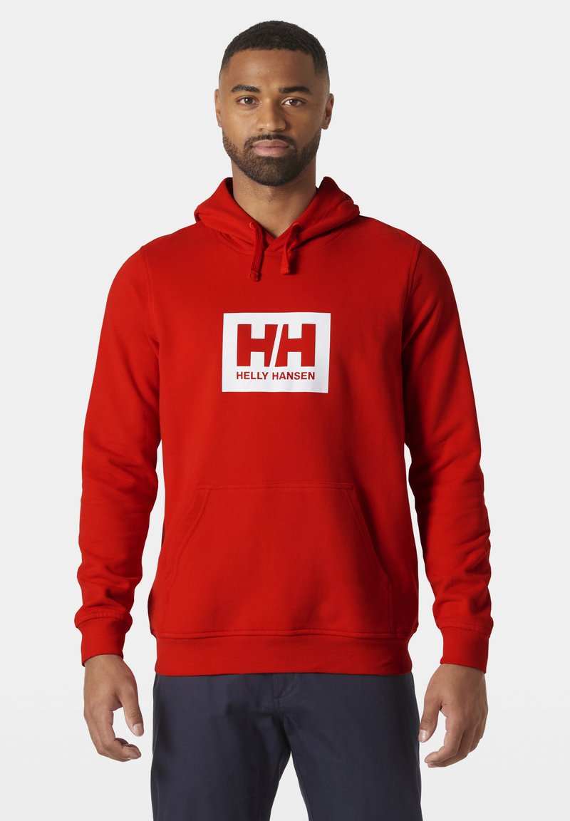 Sudadera roja de felpa con un bolsillo frontal. Presenta un logotipo rectangular blanco con el texto "HH". Cordon ajustable en el cuello.