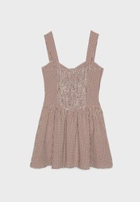 Robe sans manches à carreaux marron et blanc avec corsage smocké et jupe froncée sur fond uni.