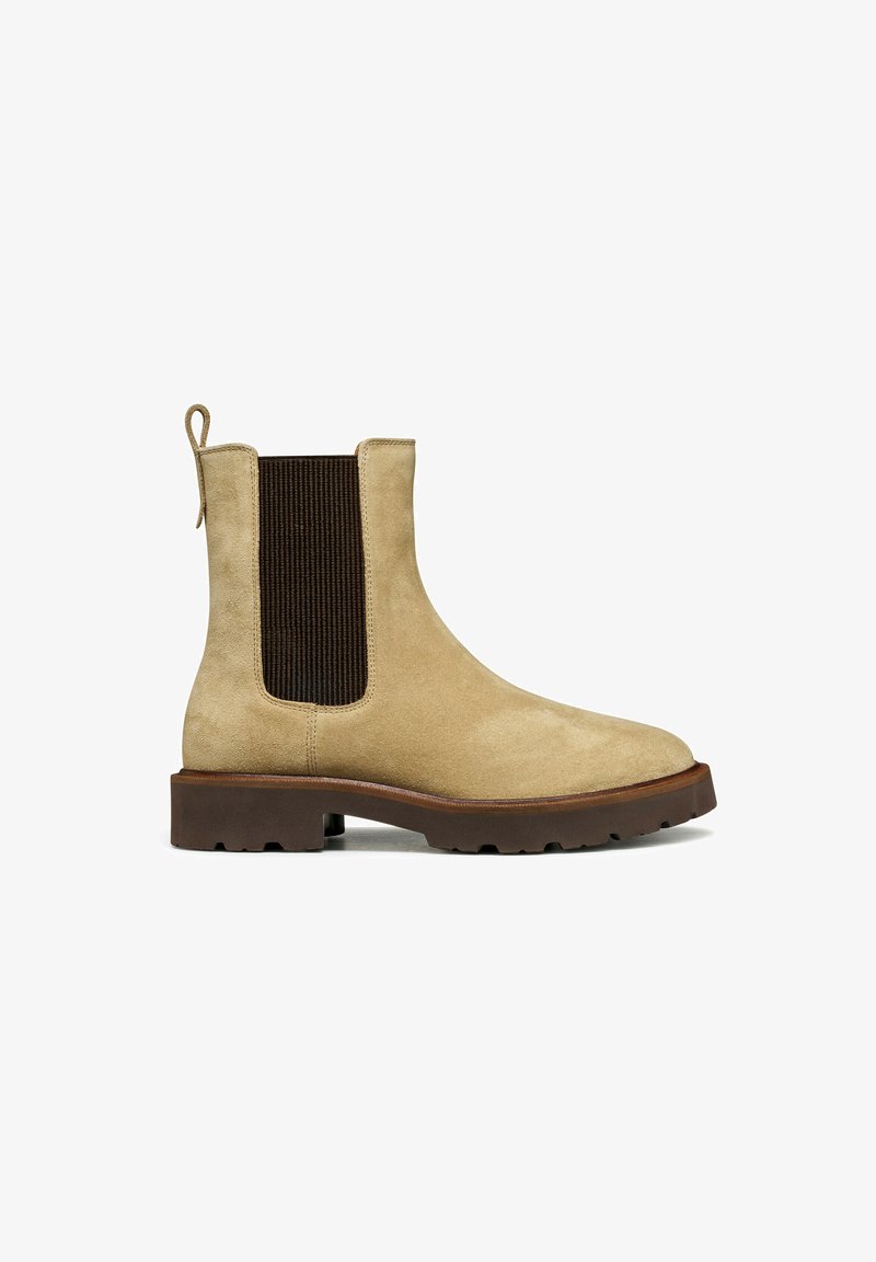 Stivale in suede beige con pannello laterale elasticizzato marrone, punta tonda e suola in gomma. Include una linguetta sul tallone per una facile calzata.