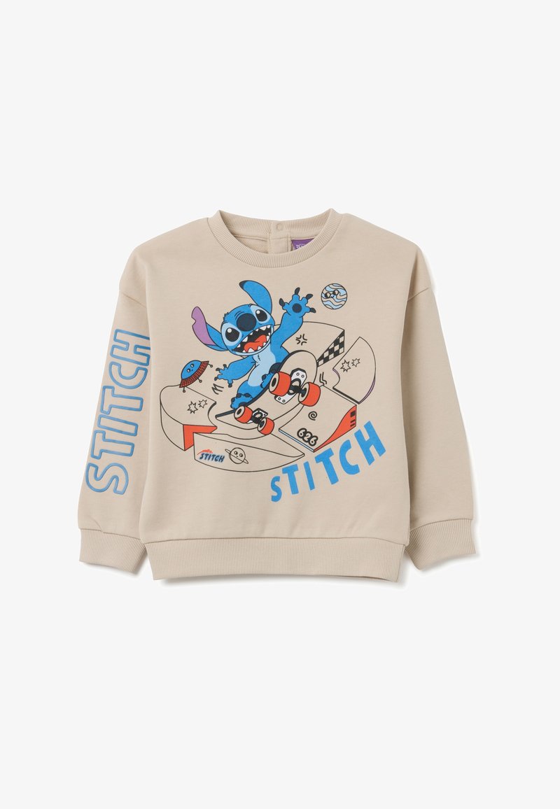 Sudadera beige con un diseño de dibujos animados colorido de un personaje alienígena azul haciendo skateboard, con la palabra "STITCH" impresa en letras azules negritas.