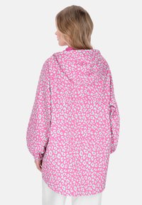 Rózsaszín leopárdmintás kapucnis dzseki laza szabással, gumírozott mandzsettákkal és sima textúrával, egészében világoskék részletekkel.