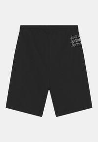 Mustat urheilushortsit, joissa on joustava vyötärö. "Farkut" painettuna harmaalla vasemmalle puolelle. Liukas kangas ja polvenmittainen malli.