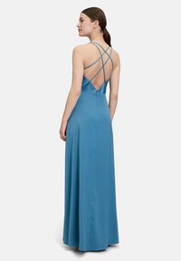 Maxikleid aus Satinmaterial, mit tiefem V-Ausschnitt im Rücken und Überkreuzträgern. Die Farbe ist Blau, mit glatter Textur und fließender Silhouette.