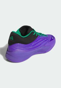 Fialová sportovní obuv s černými a zelenými akcenty. Má elegantní design, texturovaný povrch a kontrastní tkaničky. Pevně strukturovaný podpatek.
