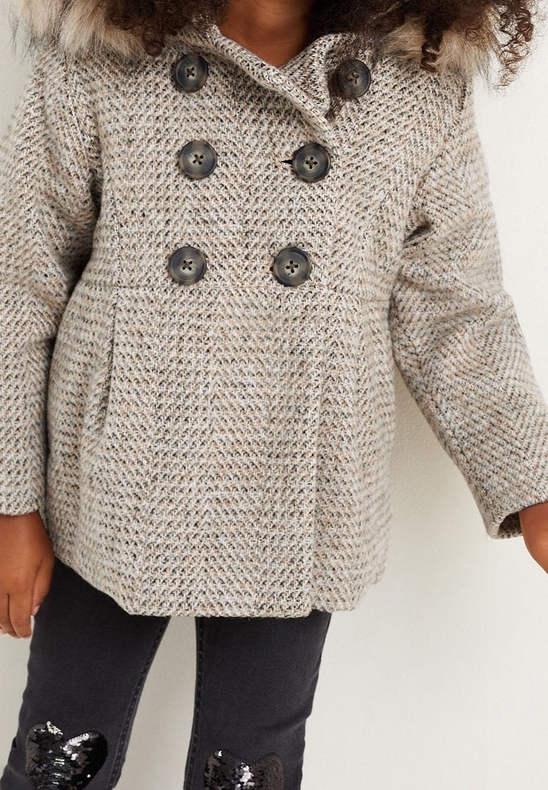 Dubbelknäppt rock i ljusgrått vävt tyg, med stora svarta knappar och en huva i konstpälsg. Slät textur och strukturerad passform.