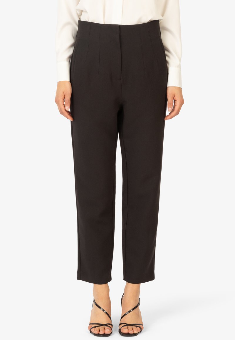 Schwarze maßgeschneiderte Hose mit hoher Taille, gefaltetem Vorderteil und geradem Bein. Hergestellt aus glattem Stoff und kombiniert mit schwarzen Riemchensandalen.