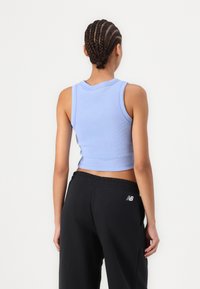 Lyseblå ribbet crop tank topp med rund halslinning, paret med svarte joggebukser med elastisk liv og logodetalj.
