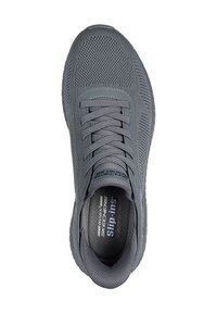 Scarpa sportiva grigia con tomaia in mesh testurizzato, allacciatura tradizionale e soletta ammortizzata. Presenta un marchio discreto sul lato e sulla soletta.