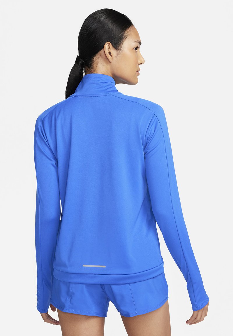 Chaqueta atlética de manga larga en azul brillante, hecha de tejido suave, con un cuello alto y un acento reflectante en la parte baja de la espalda.