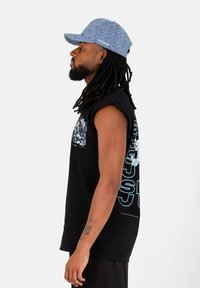 T-shirt nera senza maniche con testo grafico blu, abbinata a un cappellino azzurro chiaro con stampa a tutto campo e visiera curvata.