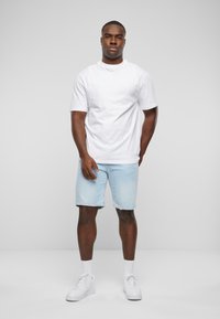 Fehér pamut póló, világoskék farmer sort, fehér sportcipő és fehér boka zokni. Egyszerű dizájn, laza fazon, látható minták nélkül.