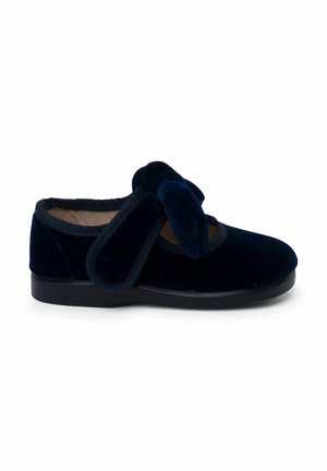 Chausson en velours bleu marine avec une semelle rembourrée et une large bride réglable sur le dessus pour un maintien facile et un confort optimal.