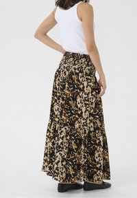 Maxi skirt with a tiered design, featuring a leopard print pattern in black, brown, and cream. Elastic waistband and soft fabric.