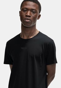 Maglietta nera a maniche corte realizzata in un tessuto morbido. Presenta un discreto logo Calvin Klein sul davanti. Design semplice, moderno e aderente.