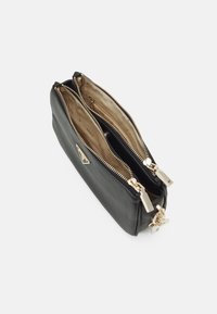 Sort lædertaske med to rum, guld lynlåse og hardware accenter. Indersiden er foret med et lyst beige stof.