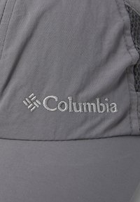 Gorra gris hecha de tela ligera con un logotipo en plata bordado. El diseño incluye paneles laterales de malla para ventilación.