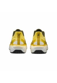 Een paar gele en witte sportschoenen gezien vanuit de achterkant, met zwarte buitenzoolprofielen en stoffen trek-tabs op de hielen.