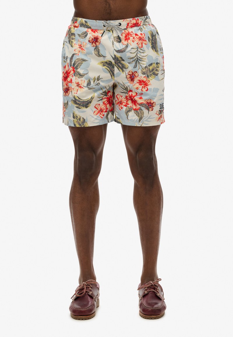 Bloemrijke zwemshorts met een lichtblauwe achtergrond, rode bloemen en groene bladeren; voorzien van een elastische tailleband en een trekkoord.
