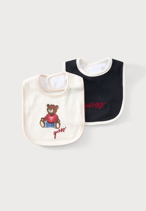 Deux bavoirs pour bébé, un blanc avec un ours en peluche et le texte « guess », l'autre noir avec le texte « guess » rouge, tous deux avec bordure blanche et fermeture Velcro au cou.