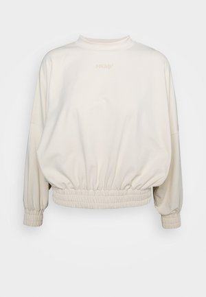 Sweat-shirt à manches longues couleur crème avec taille et poignets élastiqués, col montant, et logo discret centré près de l'encolure.